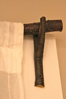 an old wooden cross hanging from the side of a white curtain in front of a beige wall