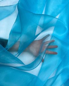 a person's hand under a blue sheer fabric