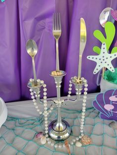 a silver candelabra with white pearls and seashells on the table