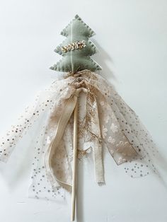 a christmas tree made out of sheer fabric and wooden dows on a white surface