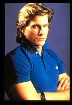 an image of a man with his arms crossed in front of him wearing a blue shirt