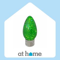 a green light bulb sitting on top of a white house with the words at home above it