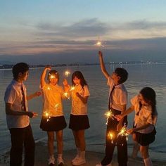 a group of young people standing next to each other holding sparklers