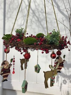 a christmas decoration hanging from the side of a white building with red ornaments and deer figurines