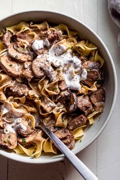 a white bowl filled with pasta and meat