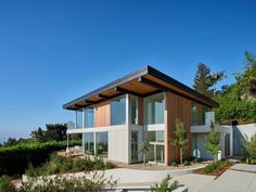 a modern house with lots of windows on the roof and side walls that overlooks trees