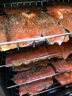 salmon cooking in an oven with seasoning on the top and bottom racks full of them