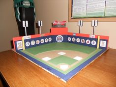 a baseball field made out of cardboard sitting on top of a wooden table