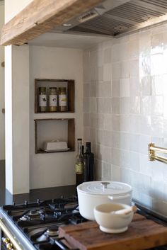 a white bowl sitting on top of a wooden cutting board in a kitchen next to a stove