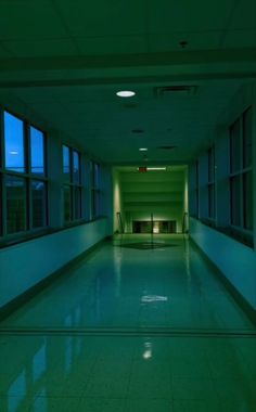 an empty hallway with large windows at night