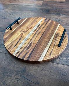 a wooden cutting board sitting on top of a hard wood floor with two black handles