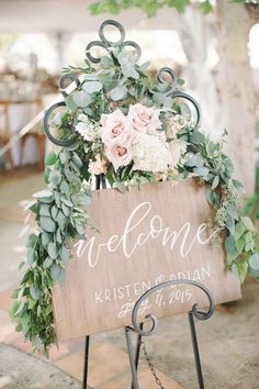 a wooden welcome sign with flowers and greenery