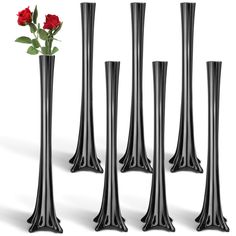 four tall black vases with one red rose in it and the other two are empty