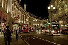 a busy city street at night with double decker buses