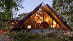 a very nice looking house in the middle of some grass and trees with lights on