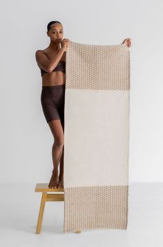 a woman standing on a stool holding up a towel