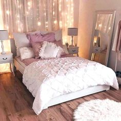 a white bed sitting in a bedroom next to a window filled with curtains and lights