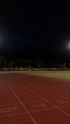 an empty running track at night with lights in the sky and onlookers