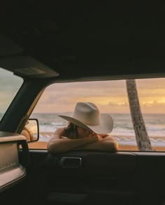 a woman wearing a white hat sitting in the back of a truck with her arms crossed