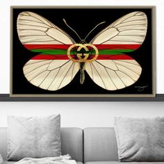 a white butterfly with red, green and yellow stripes on it's wings is hanging above a couch