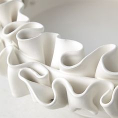 a white vase with wavy shapes on it's sides, sitting on a table