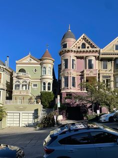 some very pretty houses in the middle of a street with cars parked on the side