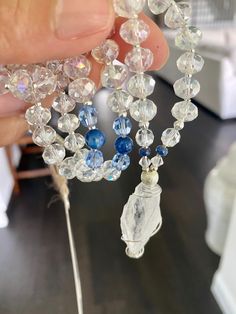 a person holding some kind of beaded necklace with blue beads and clear glass beads