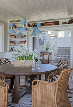 a dining room table with chairs and a basket on top of it in front of a bookshelf