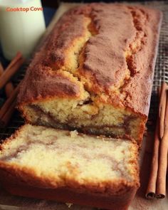 a loaf of banana bread sitting on top of a cooling rack next to cinnamon sticks