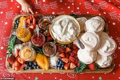 a platter filled with fruit and dips on top of a red table cloth