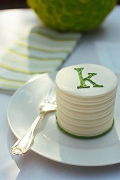 a white plate topped with a cake covered in icing and a green k on it