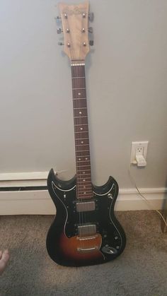 an electric guitar sitting on the floor next to a wall