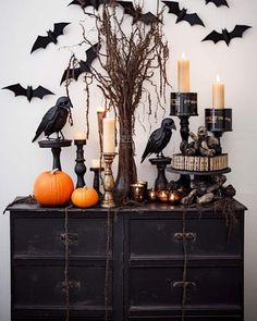 a table topped with candles and decorations next to a black cabinet filled with halloween decorations