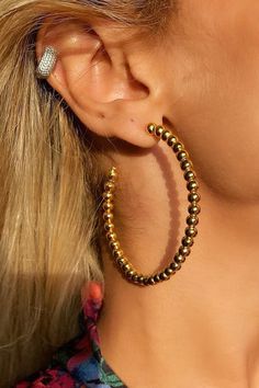 a close up of a person wearing large gold and silver hoop earrings with beads on them