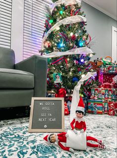 an elf sitting in front of a christmas tree with a sign that says we got a roll se la next year