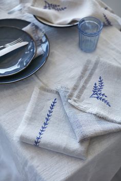 the table is set with blue and white linens, silverware, and napkins