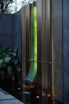 an artistic glass sculpture in the corner of a room next to a potted plant