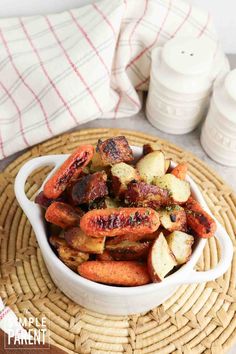 a white bowl filled with cooked carrots on top of a wicker place mat