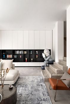 a living room filled with furniture and bookshelves next to a stair case full of books