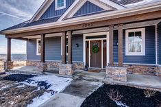 a house with blue siding and white trim on the front door is shown in winter