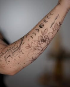 a woman's arm with flowers and planets on it