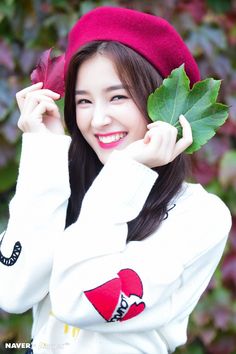 a woman in a red beret holding up a leaf