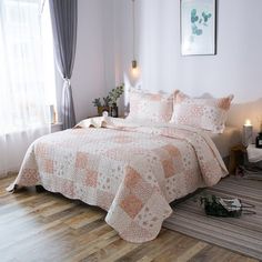 a bed sitting in a bedroom under a window next to a wooden floor with a rug on top of it