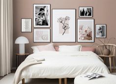 a bedroom with pink walls and pictures on the wall above the bed, along with a white footstool