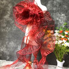 a mannequin wearing a red dress next to a vase with flowers in it