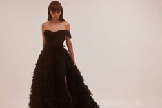 Spectacular frill-layered ball gown in black that will become a timeless wardrobe item. Featuring a one-shoulder heart-shaped neckline, a semi-transparent corset with lace-up closure on the back, and a stunning frill-layered volumetric maxi tulle skirt with a long train. Details: Material: Tulle Fabric Composition: 100% polyester Sleeves style: Sleeveless one-shoulder Silhouette: Princess dress Skirt length from waist: 115 cm Neckline: Heart-shaped neckline Back: Lace-up corset Built-in cups Lin Transparent Corset, Milla Dresses, Tulle Maxi Skirt, Sleeves Style, Timeless Wardrobe, Princess Ball Gowns, Long Train, Tulle Fabric, Semi Transparent