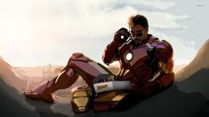 a man sitting on top of a mountain next to a giant iron man figure holding a cell phone