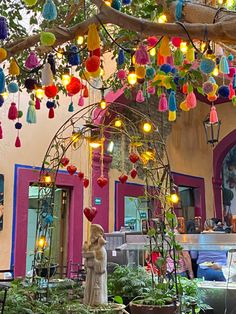 an outdoor area with potted plants and lights hanging from the ceiling in front of a building