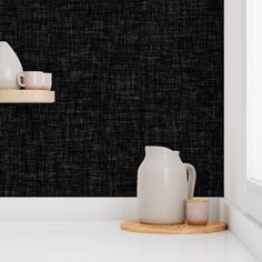 two white vases are sitting on a shelf in front of a black wallpaper