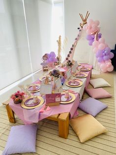 a table set up for a party with balloons, plates and napkins on it